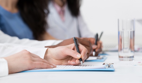 Medical Education. Doctors Writing On Paper At Conference In Hospital